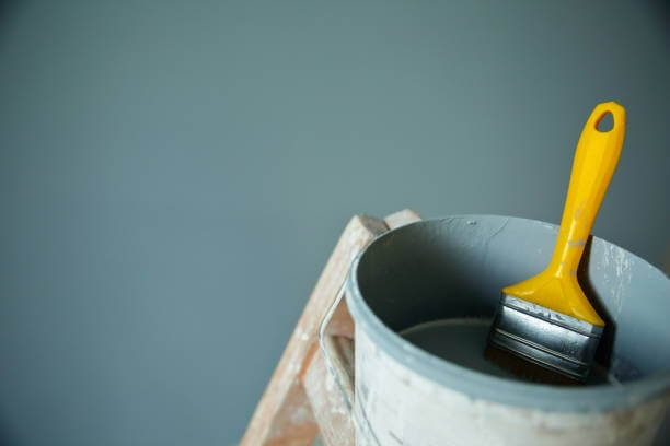 grey painting bucket with yellow painting brushes