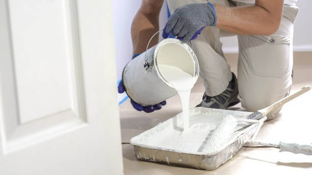 A man is making ready white paint in the pan